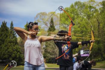 students practicing archery on a field