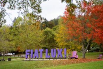 Fiat Lux sign with oversized Adirondack chair.  Fiat Lux is AU's motto meaning Let There Be Light!