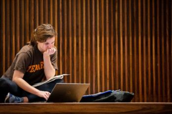 student studying with laptop in wood-paneled room